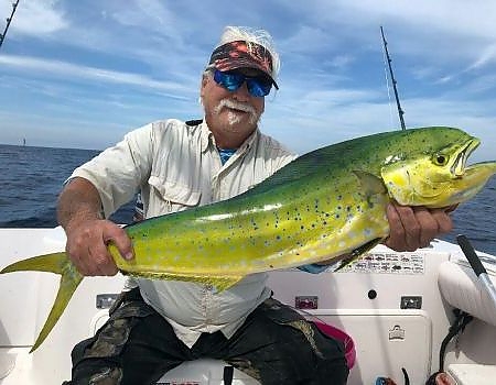  Mna sitting in boat holds up their fish with two hands