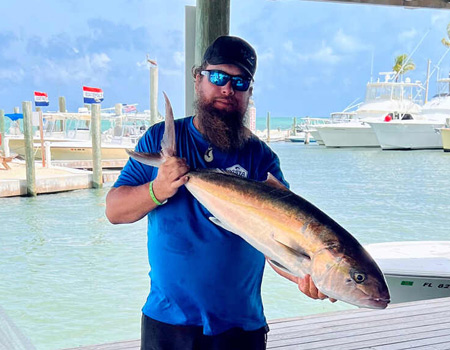 Man holds up fish caught on his trip in two hands