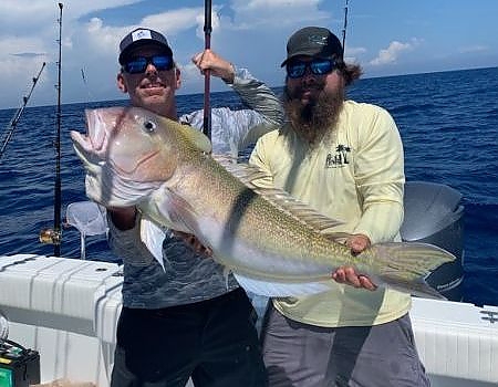 Two men hold up catch on deep fishing trip