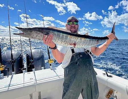 Man holds up fish caught on his trip in two hands