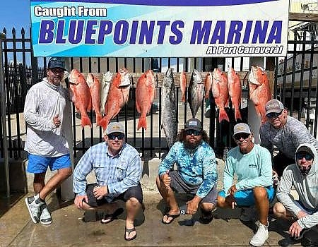 Group poses with catch in front of Bluepoints Marina sign