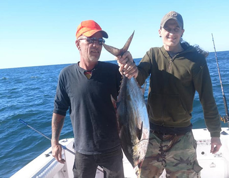 Two fishermen hold up their catch